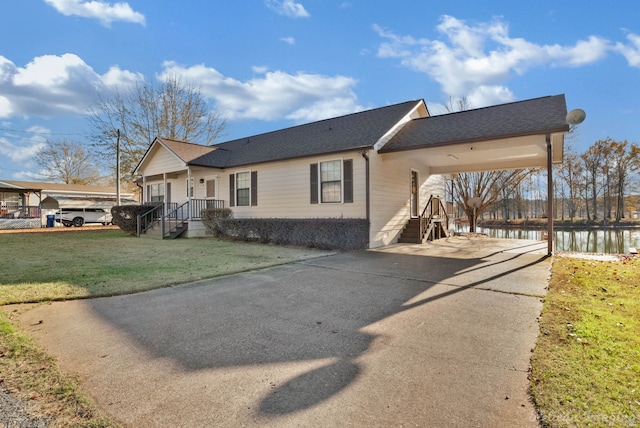 view of front of home with a carport, a water view, and a front lawn