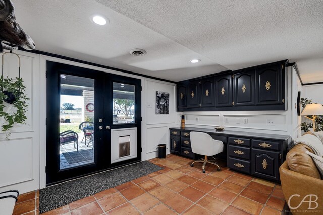 home office with light tile patterned floors, built in desk, and a textured ceiling