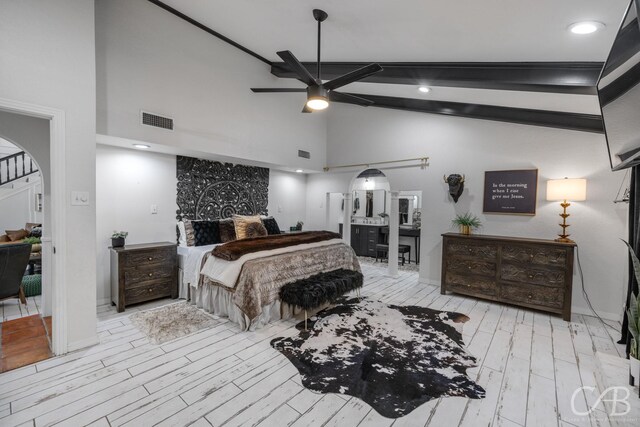 bedroom with connected bathroom, high vaulted ceiling, beamed ceiling, ceiling fan, and light wood-type flooring