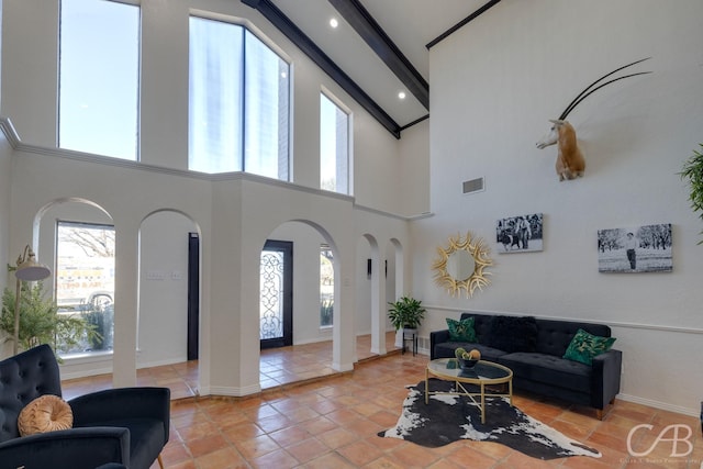 living room featuring beamed ceiling, a towering ceiling, and light tile patterned floors