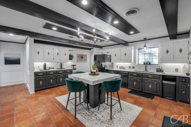 kitchen with white cabinetry, beam ceiling, black appliances, and a center island