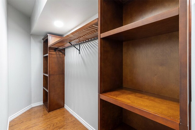 walk in closet with light hardwood / wood-style floors