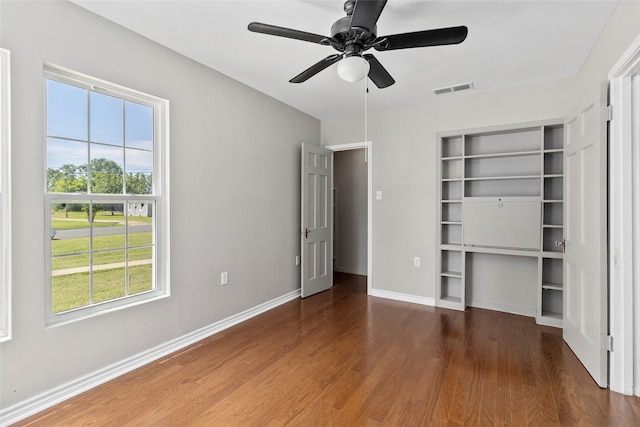 unfurnished bedroom with multiple windows, ceiling fan, and dark hardwood / wood-style floors