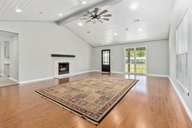 living room featuring ceiling fan, a stone fireplace, lofted ceiling with beams, wood-type flooring, and wood ceiling