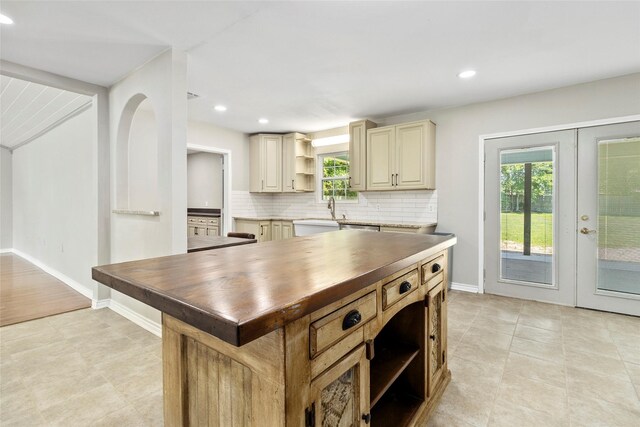 kitchen featuring dishwasher, french doors, a center island, wood counters, and backsplash