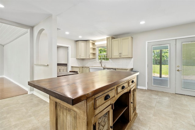 kitchen with french doors, wooden counters, dishwasher, a kitchen island, and backsplash