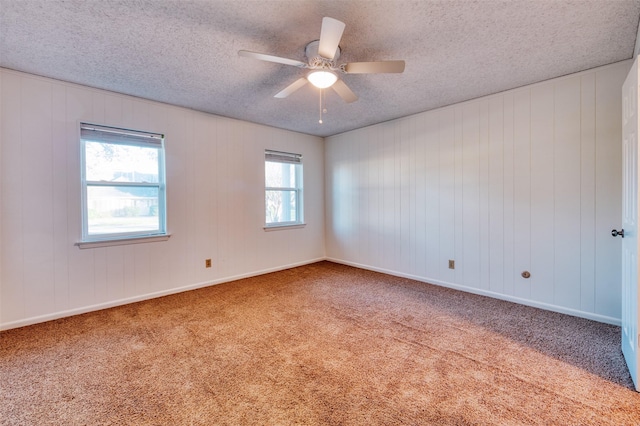 empty room with ceiling fan, carpet floors, a healthy amount of sunlight, and a textured ceiling