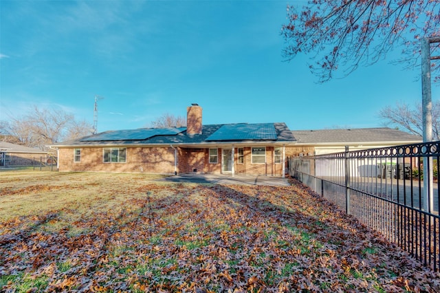 back of house featuring solar panels, a patio area, and a yard