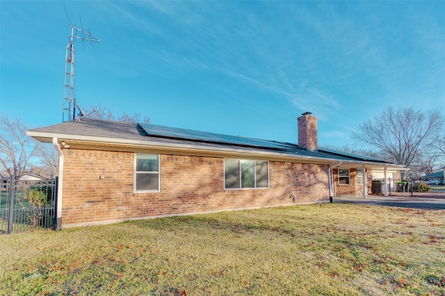 back of property with solar panels and a yard