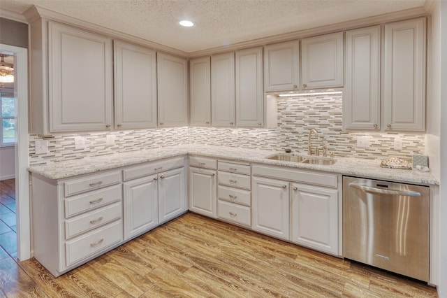 kitchen featuring light stone countertops, sink, stainless steel dishwasher, light hardwood / wood-style floors, and decorative backsplash