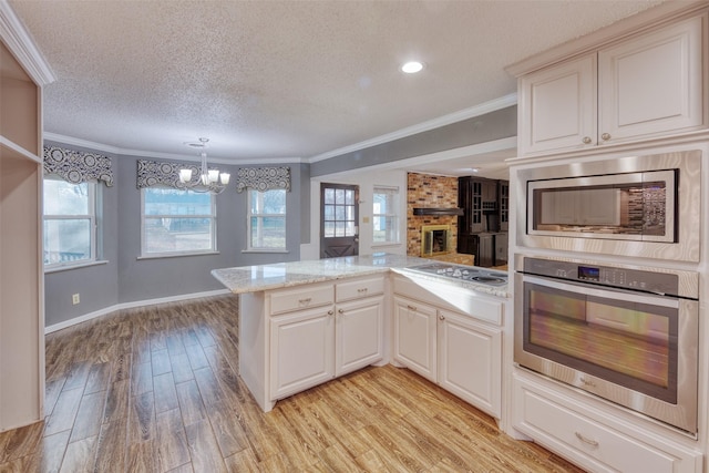 kitchen featuring kitchen peninsula, appliances with stainless steel finishes, light wood-type flooring, and a textured ceiling