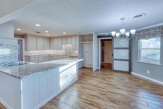 kitchen with pendant lighting, backsplash, an inviting chandelier, a textured ceiling, and kitchen peninsula