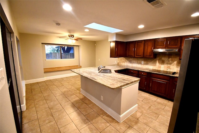 kitchen with a skylight, backsplash, black electric stovetop, ceiling fan, and kitchen peninsula