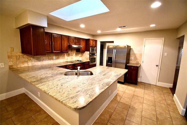 kitchen with sink, a skylight, kitchen peninsula, stainless steel appliances, and decorative backsplash