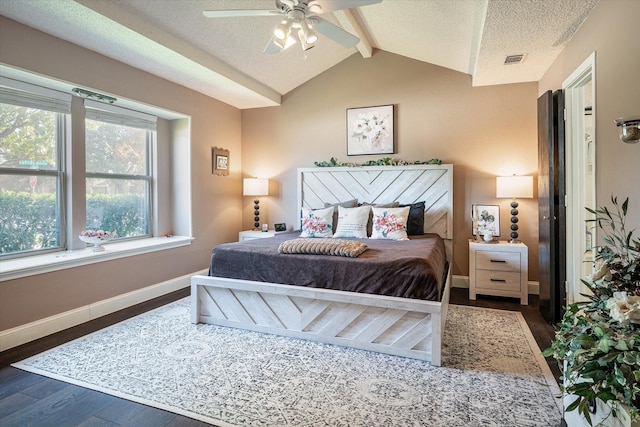 bedroom with dark hardwood / wood-style flooring, ceiling fan, lofted ceiling with beams, and a textured ceiling