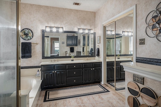 bathroom featuring a washtub, vanity, a textured ceiling, and tile patterned flooring