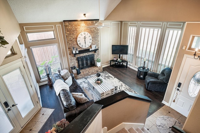 living room with ceiling fan, light hardwood / wood-style floors, high vaulted ceiling, and a brick fireplace