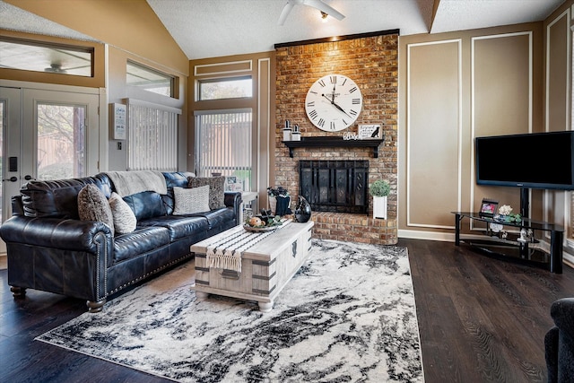 living room with vaulted ceiling, a fireplace, dark wood-type flooring, a textured ceiling, and french doors