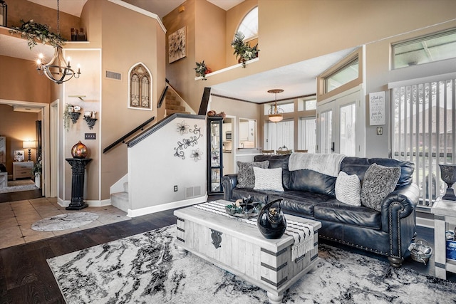 living room with a towering ceiling, dark wood-type flooring, french doors, and a chandelier