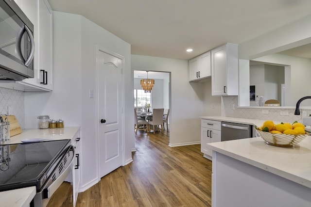 kitchen with white cabinetry, light hardwood / wood-style flooring, stainless steel dishwasher, a notable chandelier, and decorative backsplash