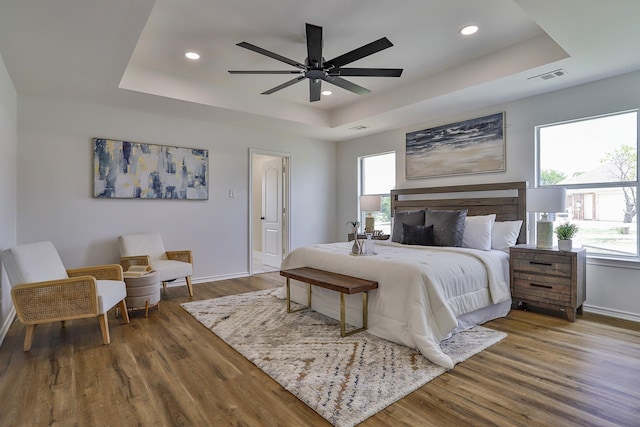 bedroom featuring a tray ceiling, ceiling fan, and dark hardwood / wood-style floors