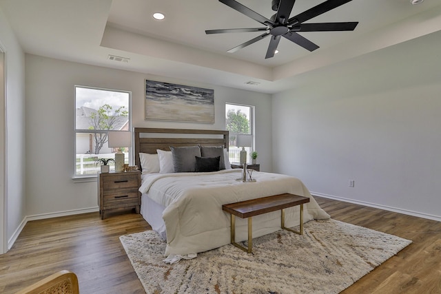 bedroom featuring a tray ceiling, ceiling fan, and dark hardwood / wood-style flooring