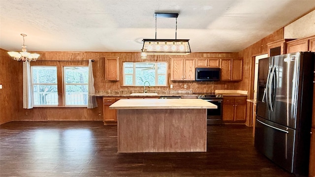 kitchen featuring a sink, dark wood finished floors, a center island, stainless steel appliances, and light countertops