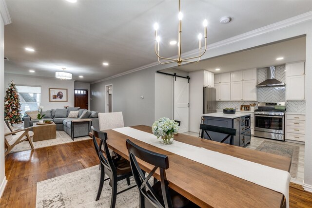 dining area featuring light wood-type flooring, crown molding, a notable chandelier, and sink