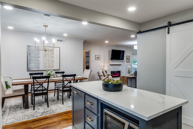 kitchen with hanging light fixtures, a center island, light hardwood / wood-style floors, built in microwave, and a barn door