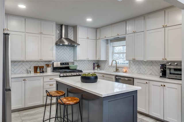 kitchen featuring white cabinetry, stainless steel appliances, wall chimney range hood, a barn door, and a kitchen island