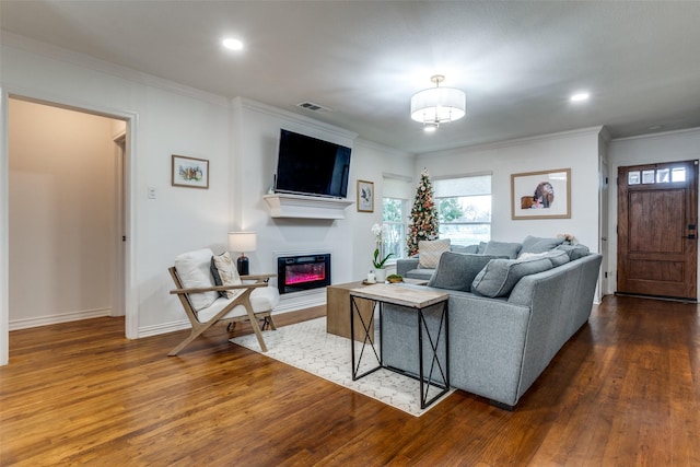 living room featuring dark hardwood / wood-style flooring, ornamental molding, and an inviting chandelier