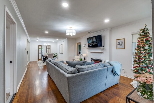 living room featuring hardwood / wood-style floors, ornamental molding, and a notable chandelier