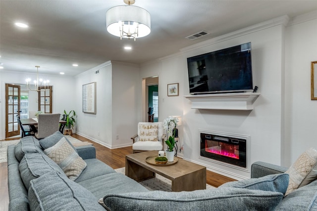 living room featuring crown molding, wood-type flooring, and an inviting chandelier