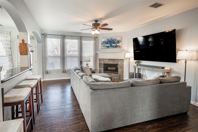 living room featuring dark hardwood / wood-style flooring, ceiling fan, and a tiled fireplace