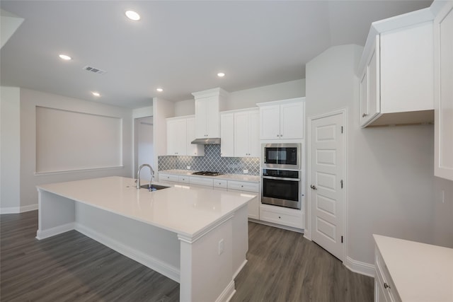 kitchen with white cabinetry, stainless steel appliances, sink, and a center island with sink