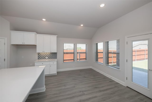 kitchen featuring white cabinetry, vaulted ceiling, dark hardwood / wood-style floors, and backsplash