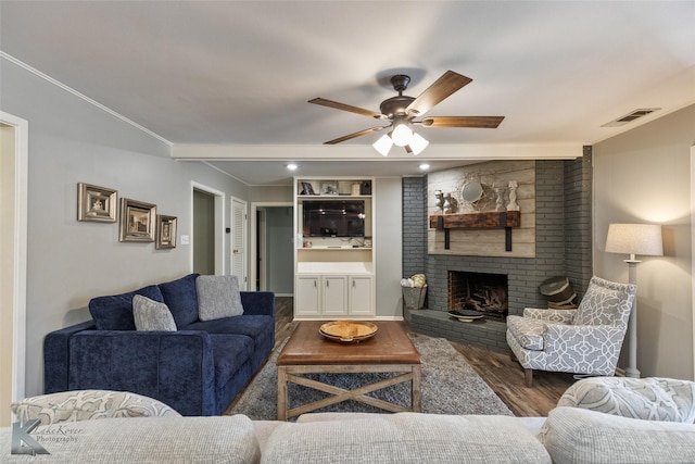 living room with ceiling fan, a brick fireplace, crown molding, and dark hardwood / wood-style floors