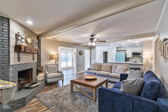 living room with hardwood / wood-style flooring, ceiling fan, a brick fireplace, and sink