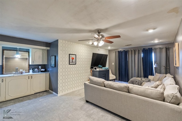 living room featuring light colored carpet, ceiling fan, and sink