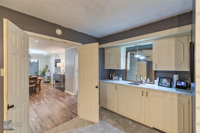 kitchen featuring sink, decorative light fixtures, light carpet, and a chandelier