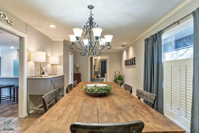 dining room with wood-type flooring, crown molding, and a chandelier