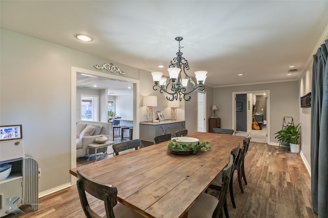 dining space featuring wood-type flooring, crown molding, and a chandelier