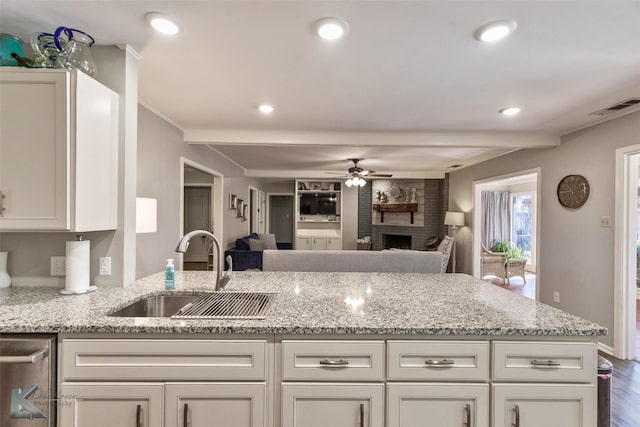 kitchen with sink, white cabinets, a brick fireplace, and light stone countertops