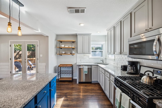 kitchen featuring pendant lighting, sink, dark wood-type flooring, appliances with stainless steel finishes, and light stone counters