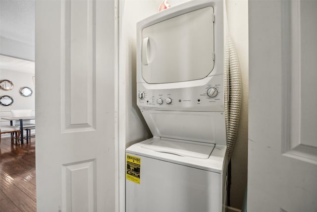 laundry area with hardwood / wood-style flooring and stacked washer / dryer