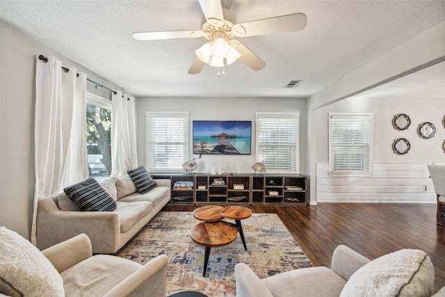 living room with ceiling fan, dark hardwood / wood-style flooring, and a textured ceiling