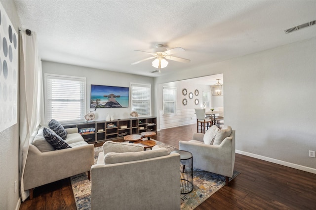 living room featuring ceiling fan, dark wood-type flooring, and a textured ceiling