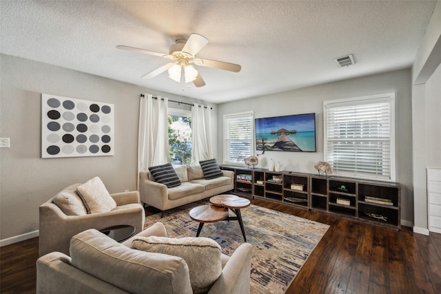 living room featuring ceiling fan, dark hardwood / wood-style floors, and a textured ceiling