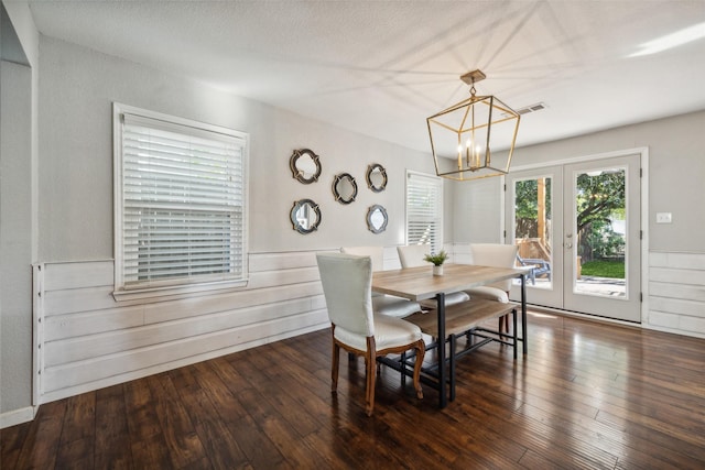 dining room with dark hardwood / wood-style flooring, wooden walls, french doors, and a chandelier