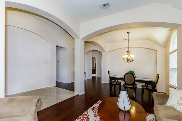 dining area featuring dark hardwood / wood-style flooring, vaulted ceiling, and a notable chandelier